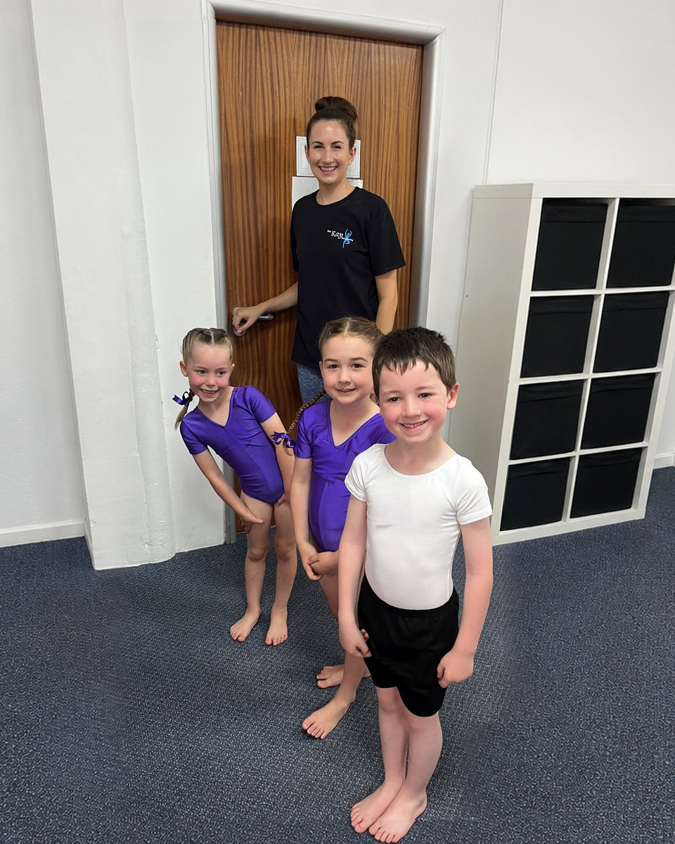 Three young Kay Academy dancers smiling with their teacher